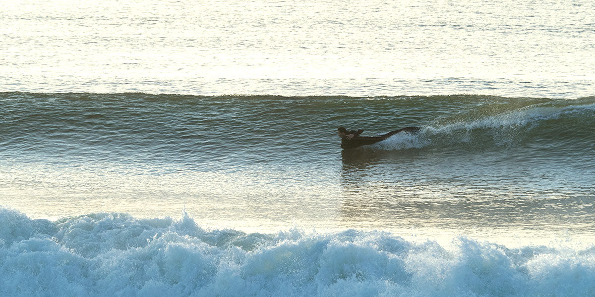 Surfer riding a wave at high speed on a custom Warpmats surf mat